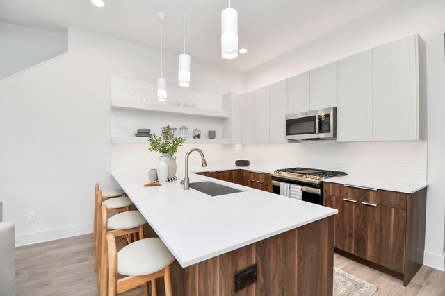 kitchen with white cabinets, decorative light fixtures, stainless steel appliances, and a breakfast bar area