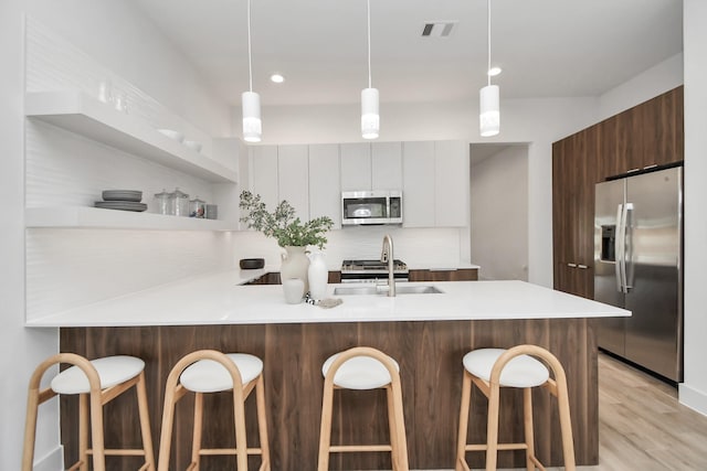 kitchen with sink, white cabinetry, a kitchen breakfast bar, stainless steel appliances, and kitchen peninsula