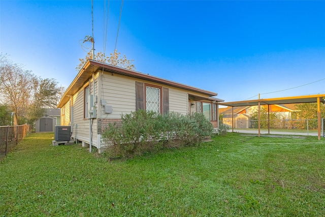 back of property featuring a lawn, cooling unit, and a storage unit