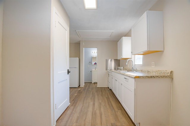 kitchen with sink, white cabinets, light hardwood / wood-style floors, and white refrigerator