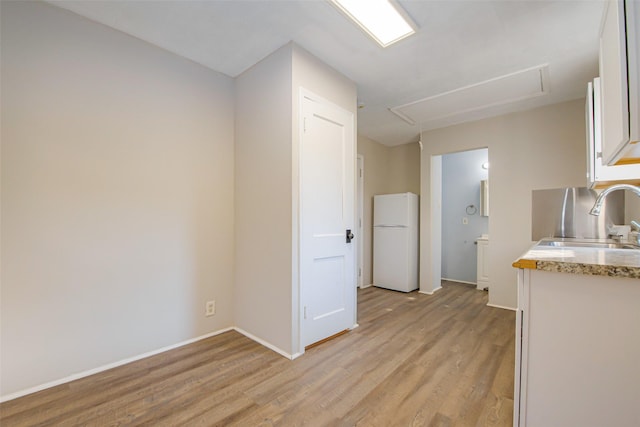 kitchen with white refrigerator, white cabinetry, light hardwood / wood-style flooring, and sink