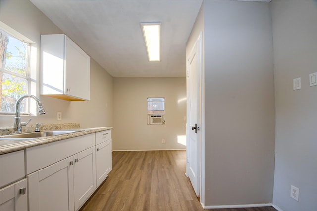 interior space with white cabinets, cooling unit, light wood-type flooring, and sink