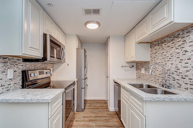 kitchen featuring white cabinetry, sink, light hardwood / wood-style flooring, decorative backsplash, and appliances with stainless steel finishes