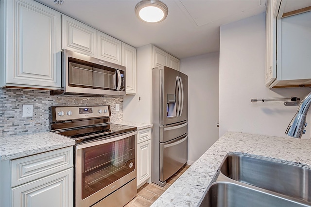 kitchen featuring appliances with stainless steel finishes, sink, white cabinetry, and light stone counters