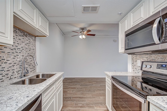 kitchen featuring light wood-type flooring, tasteful backsplash, stainless steel appliances, sink, and white cabinets