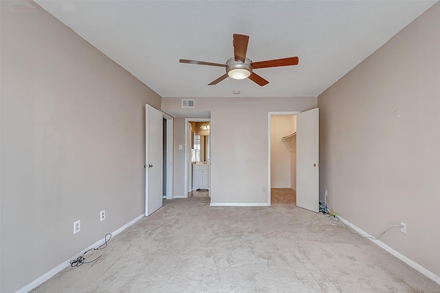 unfurnished bedroom featuring ceiling fan, a walk in closet, light carpet, and a closet