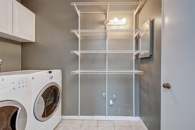 laundry area featuring separate washer and dryer, light tile patterned floors, and cabinets