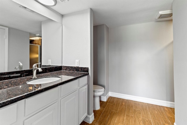 bathroom with wood-type flooring, vanity, and toilet