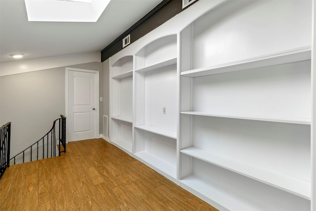 walk in closet featuring wood-type flooring and a skylight