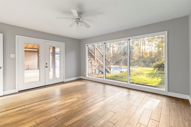 unfurnished room with french doors, light wood-type flooring, a wealth of natural light, and ceiling fan