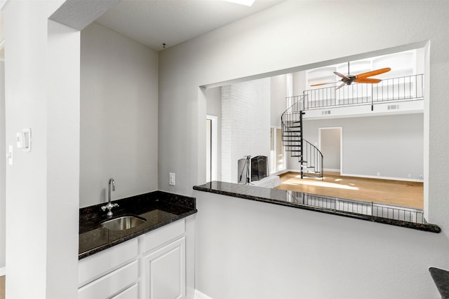 kitchen featuring white cabinetry, sink, ceiling fan, and dark stone counters