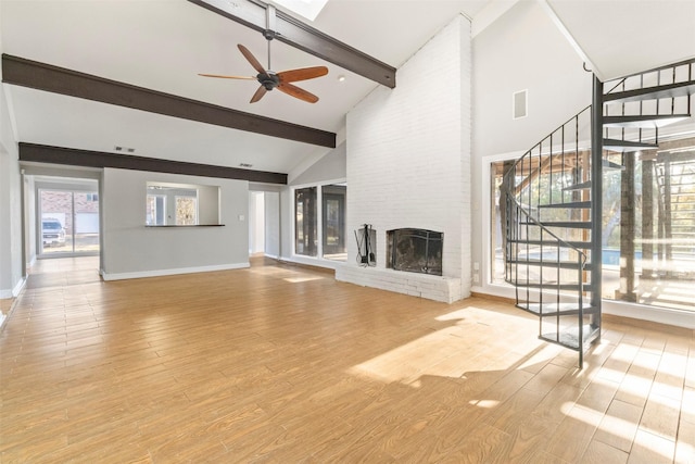 unfurnished living room featuring ceiling fan, a brick fireplace, beamed ceiling, high vaulted ceiling, and wood-type flooring