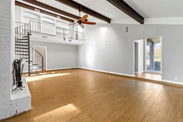 unfurnished living room with ceiling fan and beam ceiling