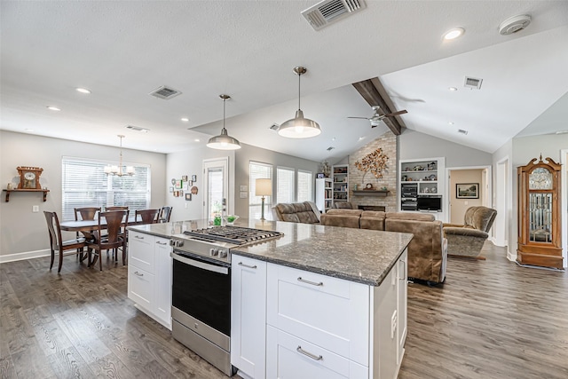 kitchen with a center island, white cabinetry, dark stone counters, and stainless steel range with gas stovetop