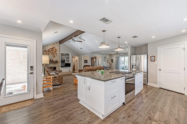 kitchen featuring a center island, dark stone counters, white cabinets, hanging light fixtures, and appliances with stainless steel finishes