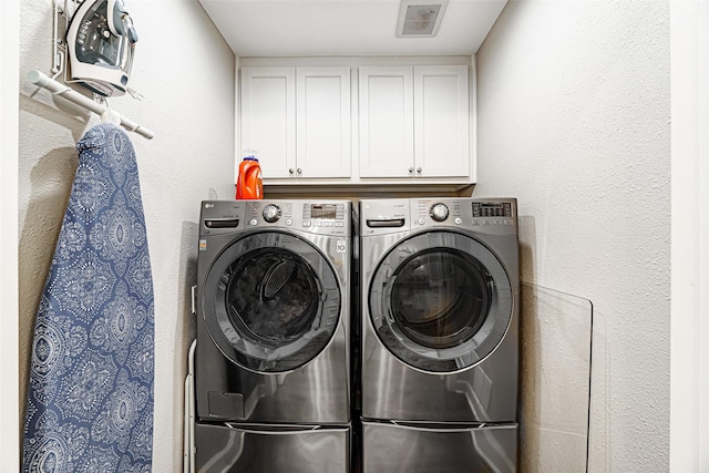 clothes washing area with washer and clothes dryer and cabinets