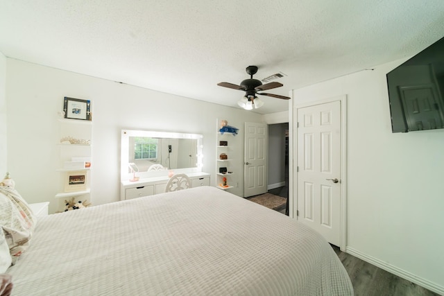 bedroom with a textured ceiling, ceiling fan, and dark wood-type flooring