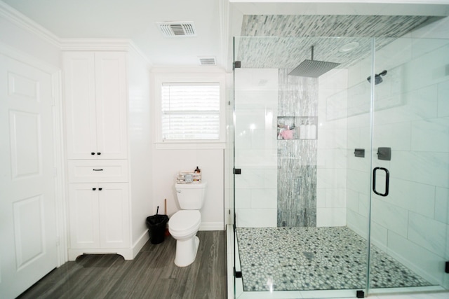 bathroom featuring hardwood / wood-style flooring, toilet, a shower with door, and ornamental molding