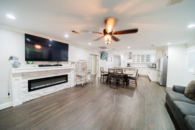 living room with crown molding, a fireplace, ceiling fan, and dark hardwood / wood-style floors