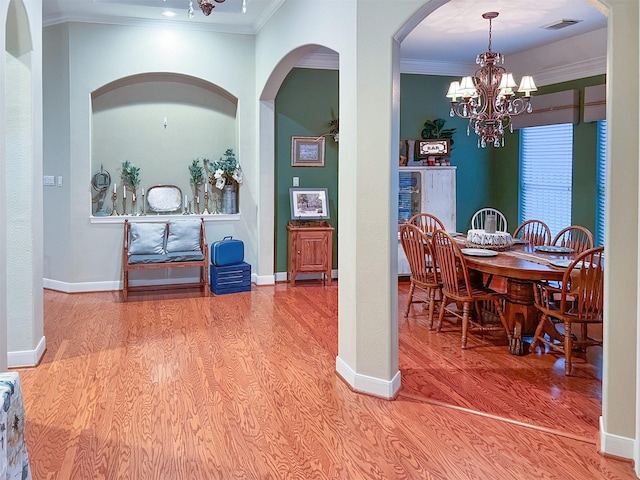 dining room with wood-type flooring, ornamental molding, and a notable chandelier