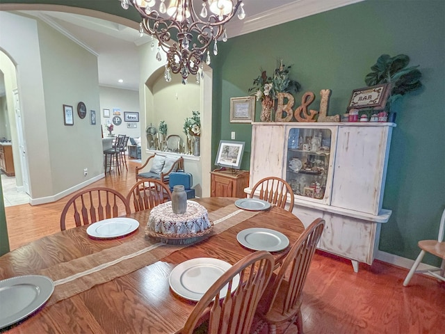 dining room with hardwood / wood-style flooring, ornamental molding, and an inviting chandelier