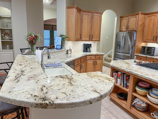 kitchen featuring tasteful backsplash, stainless steel fridge with ice dispenser, sink, kitchen peninsula, and a breakfast bar area