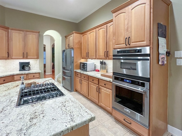 kitchen featuring light stone counters, light tile patterned flooring, stainless steel appliances, and tasteful backsplash