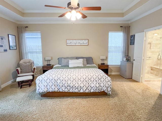 carpeted bedroom with ceiling fan, crown molding, a tray ceiling, and ensuite bath