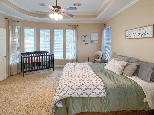 carpeted bedroom featuring ceiling fan, a raised ceiling, and ornamental molding