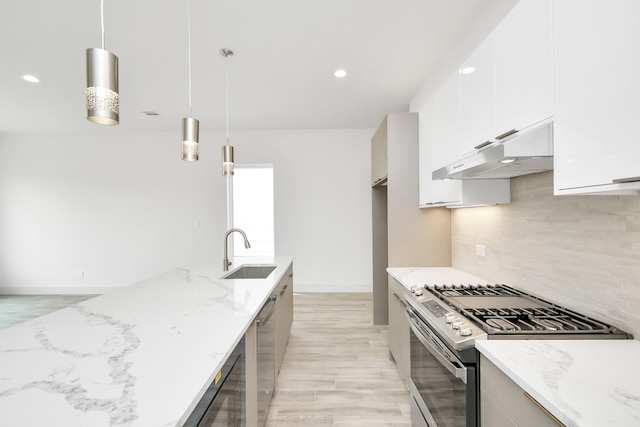 kitchen with light stone counters, ventilation hood, stainless steel appliances, sink, and hanging light fixtures