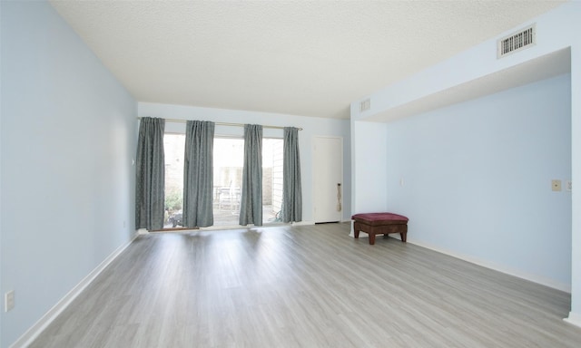 spare room with light wood-type flooring and a textured ceiling