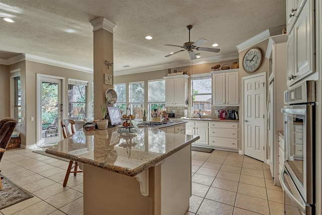 kitchen featuring white cabinetry, light stone countertops, a kitchen island, a breakfast bar, and light tile patterned floors