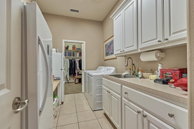 washroom featuring washing machine and clothes dryer, sink, light tile patterned floors, and cabinets