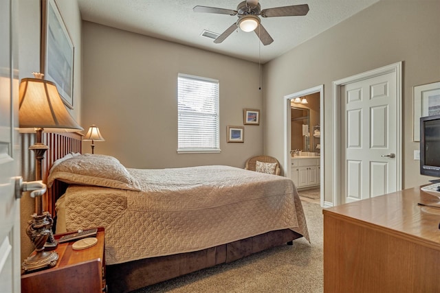 carpeted bedroom with ensuite bath and ceiling fan