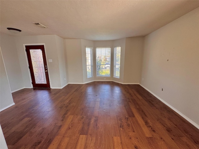 unfurnished room featuring a textured ceiling and dark hardwood / wood-style floors