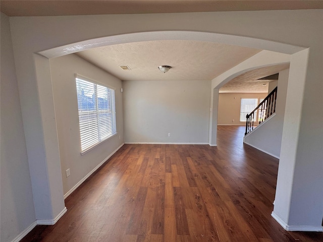 unfurnished room featuring a textured ceiling and dark hardwood / wood-style floors