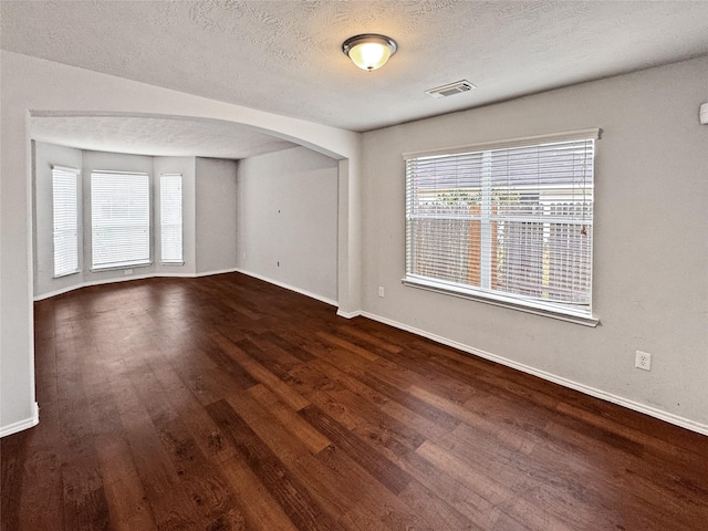 empty room featuring a textured ceiling and dark hardwood / wood-style flooring