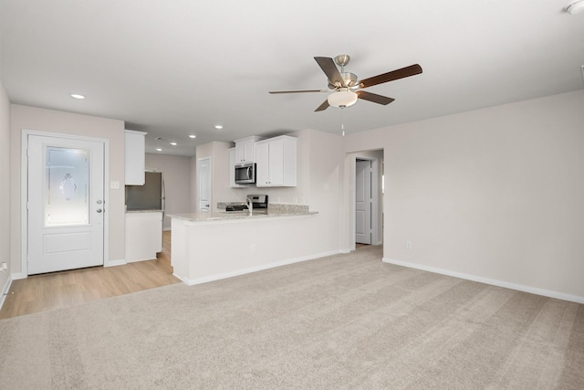 unfurnished living room featuring light colored carpet and ceiling fan