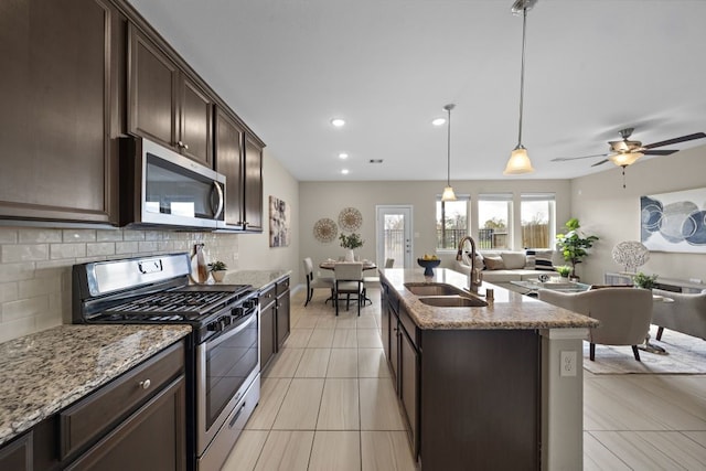 kitchen featuring dark brown cabinetry, sink, hanging light fixtures, a center island with sink, and stainless steel appliances