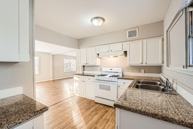 kitchen featuring sink, light wood-type flooring, gas range gas stove, white cabinetry, and kitchen peninsula