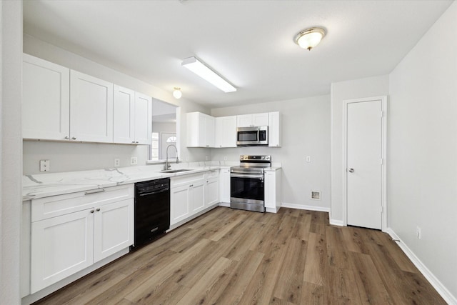 kitchen with white cabinets, sink, appliances with stainless steel finishes, light stone counters, and wood-type flooring