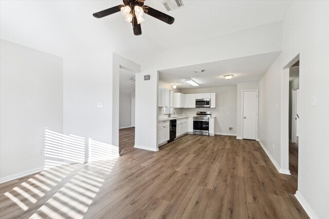 unfurnished living room featuring hardwood / wood-style floors, vaulted ceiling, ceiling fan, and sink