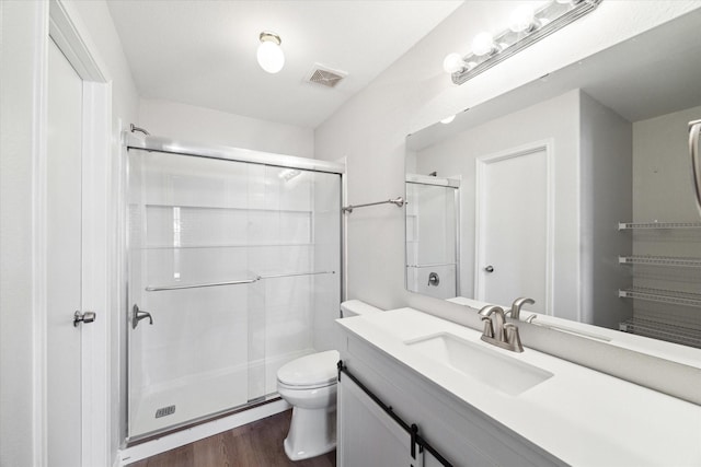 bathroom with an enclosed shower, vanity, toilet, and wood-type flooring