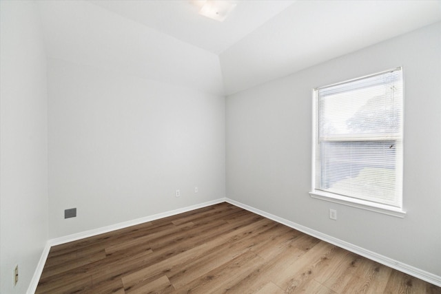 unfurnished room featuring vaulted ceiling and hardwood / wood-style flooring