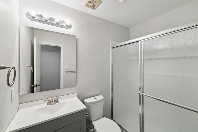 bathroom with an enclosed shower, vanity, and toilet