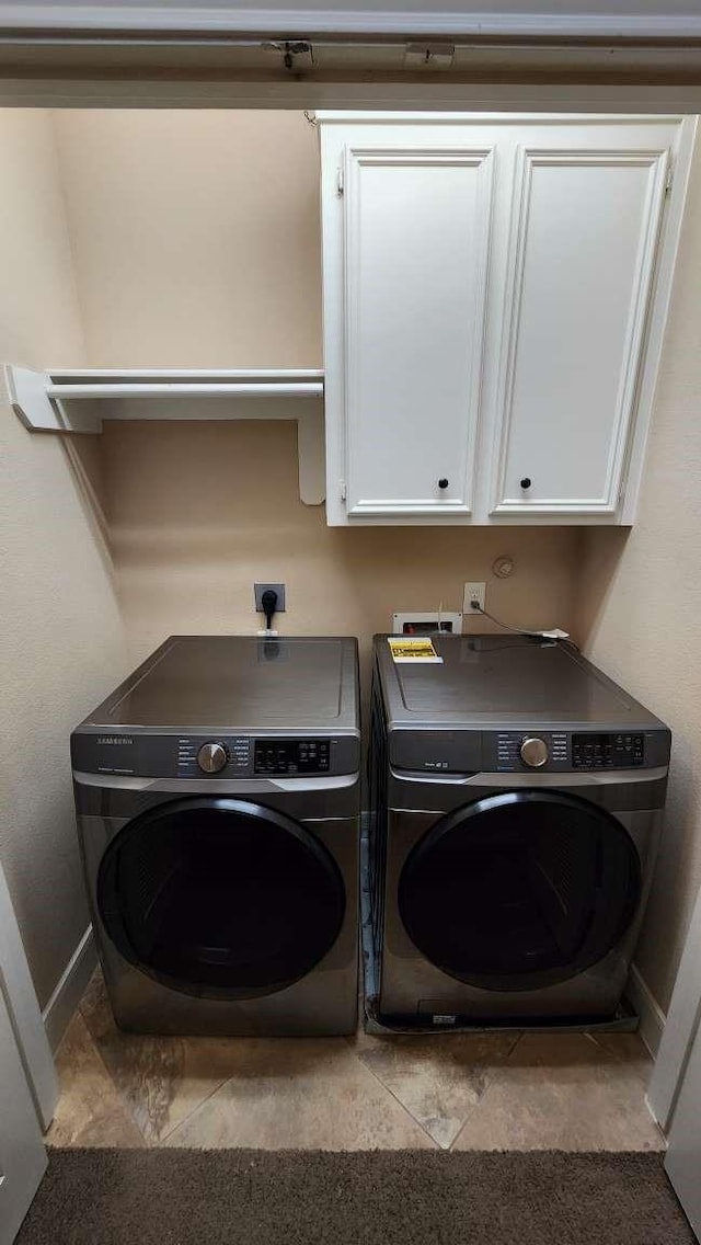 laundry area featuring washer and clothes dryer and cabinets