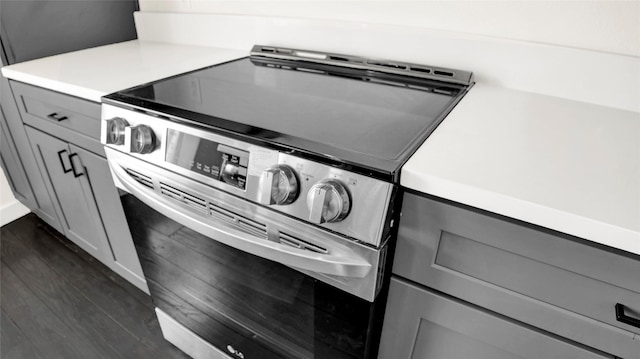 kitchen with gray cabinetry, dark wood-type flooring, and stainless steel electric range