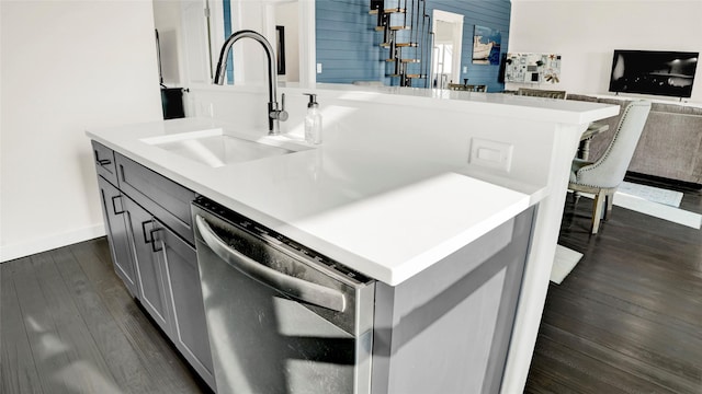 kitchen with stainless steel dishwasher, a kitchen island with sink, dark wood-type flooring, sink, and gray cabinets