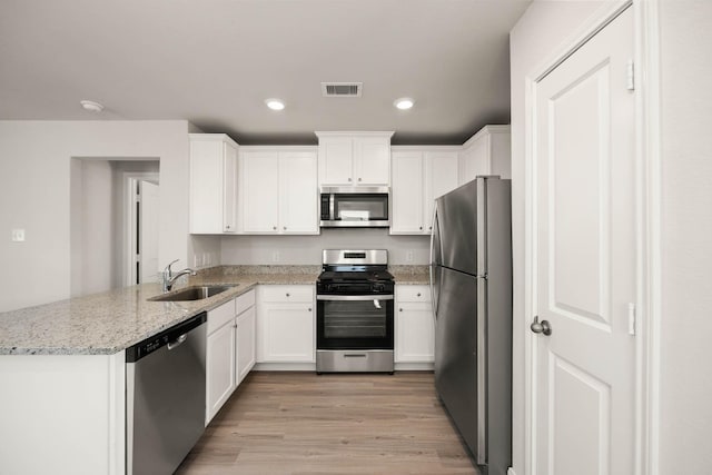 kitchen featuring white cabinets, sink, light hardwood / wood-style floors, light stone counters, and stainless steel appliances