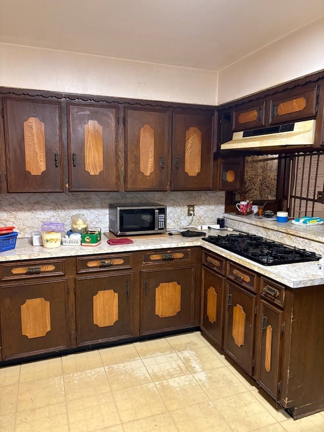 kitchen with backsplash, dark brown cabinetry, and black gas stovetop